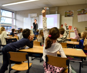 classroom of students raising hands